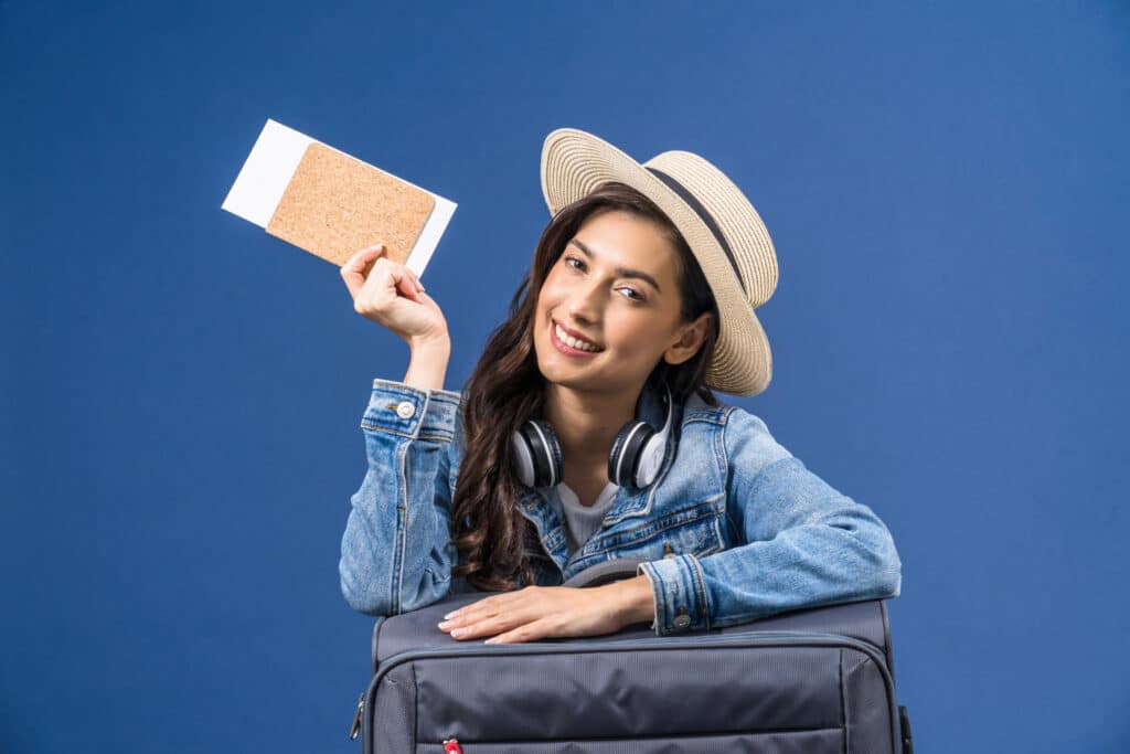 happy young asian woman holding passport with boarding pass presenting blue color