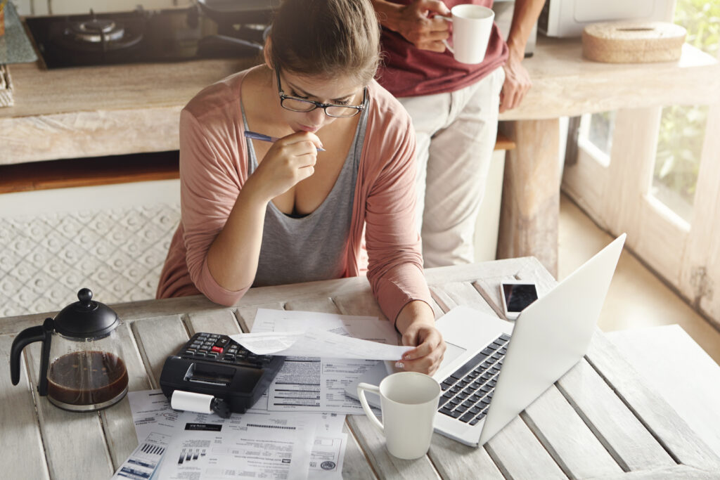 couple facing debt problems able pay out their mortgage thoughtful woman looking frustrated holding pen while managing family budget making calculations using calculator notebook pc